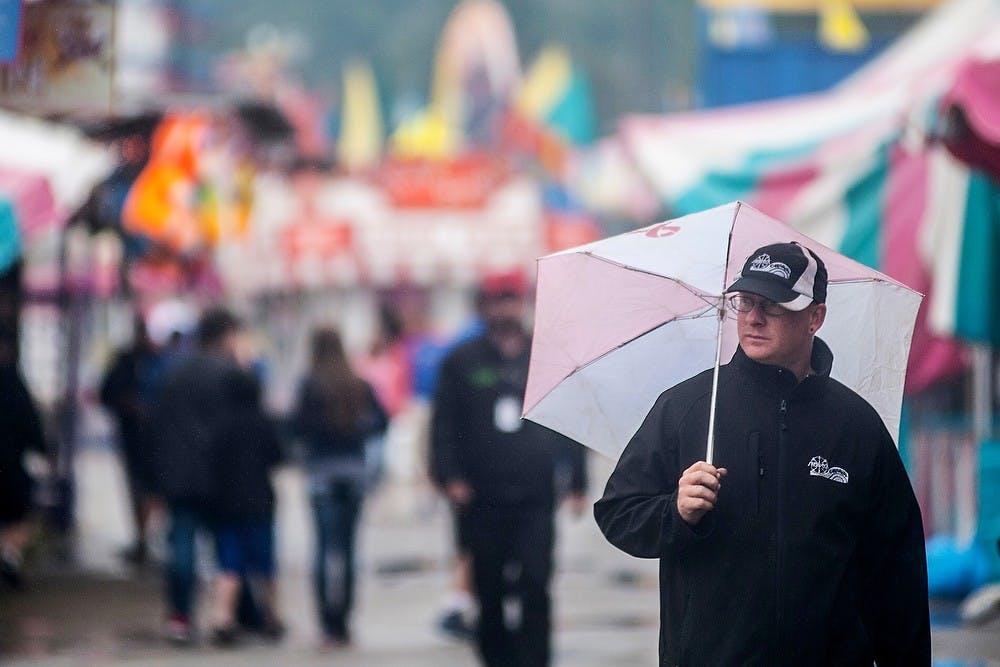 	<p>Amusement park employee and Escanaba, Mich., resident Alan Bridges walks in the rain, July 31, 2013, at the 159th annual Ingham County Fair in Mason, Mich. The weather on Wednesday dampened turnout at the fair. The six-day event features various livestock and sports shows, as well as amusement facilities. Justin Wan/The State News</p>