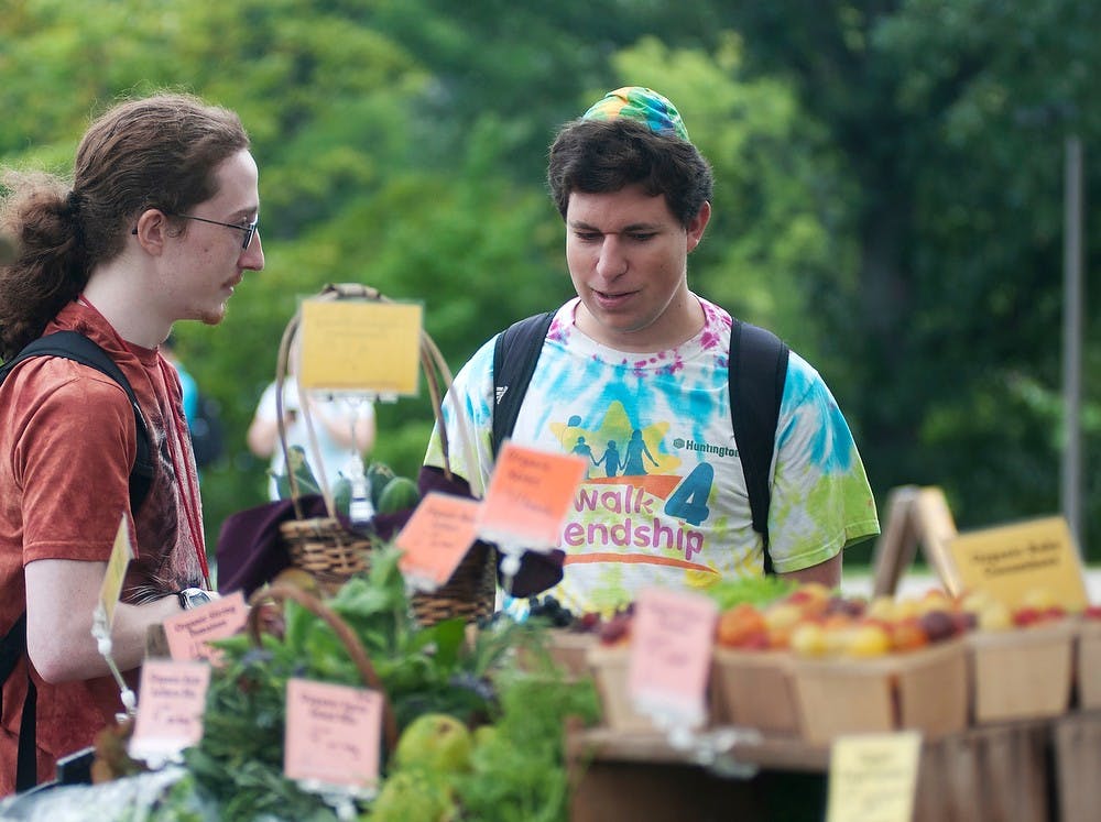 <p>Zoology junior William Leslie and environmental education sophomore Ian Zaback purchases organic food Sept. 4, 2014, at the Student Organic Farm Stand near Erickson Hall. Aerika Williams/The State News </p>