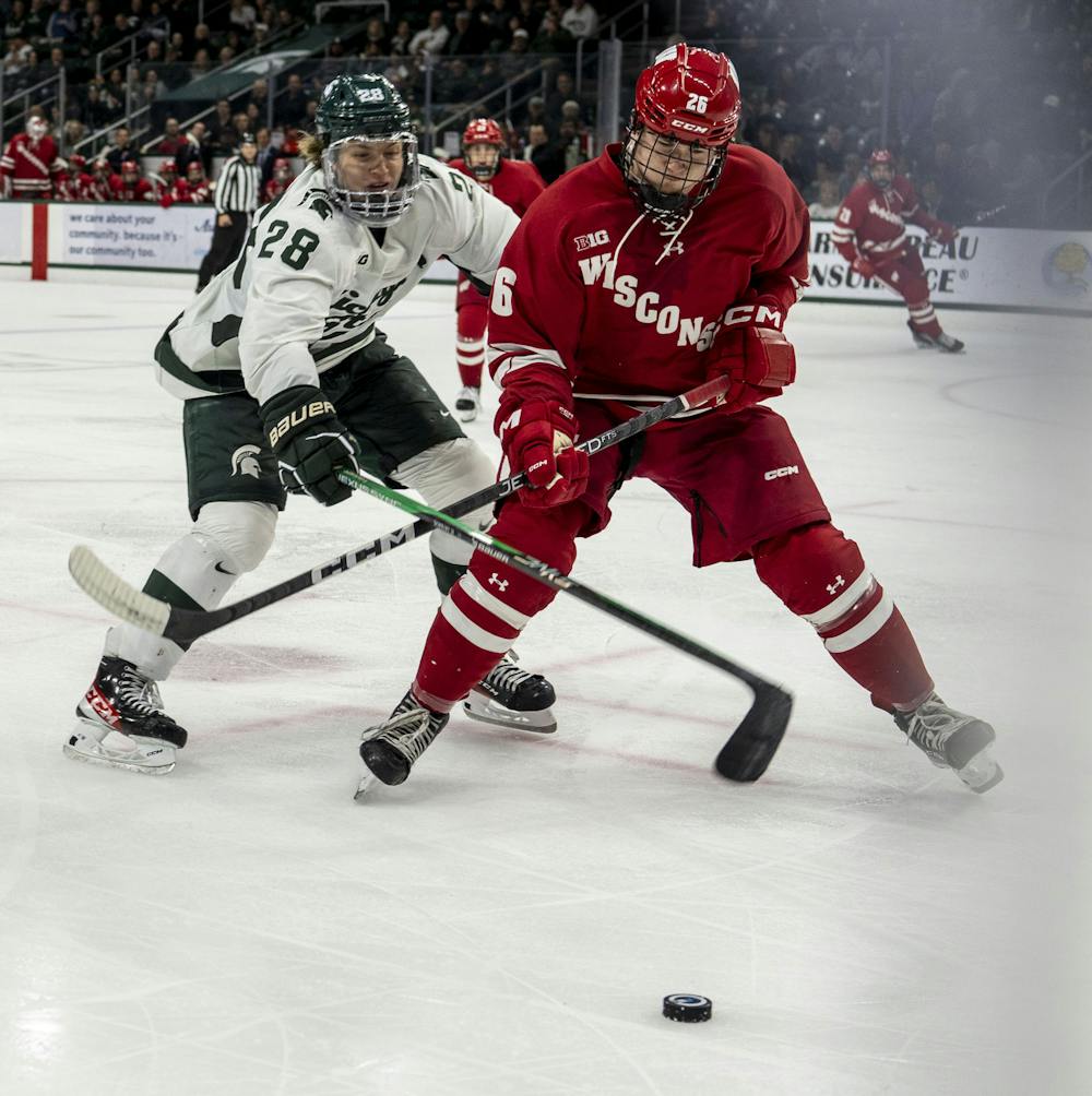 <p>Freshman forward Karsen Dorwart (28) fights for the puck during a game of ice hockey between MSU and Wisconsin at Munn Ice Arena on Nov. 4, 2022. The Spartans won, 5-0.</p>