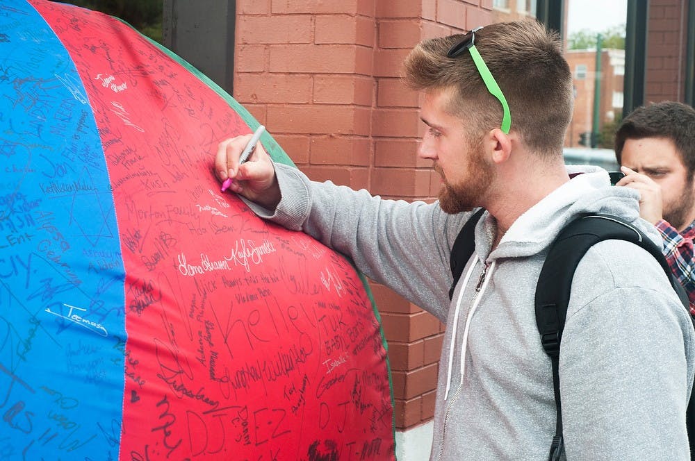 <p>Packaging senior Benjamin Hesskamp signs Zeta Beta Tau's giant gym ball to raise awareness for Sparrow Hospital and  Children’s Miracle Network Hospitals on Sept. 10, 2014, at Potbelly Sandwich Shop, 233 East Grand River Ave. Raymond Williams/The State News</p>