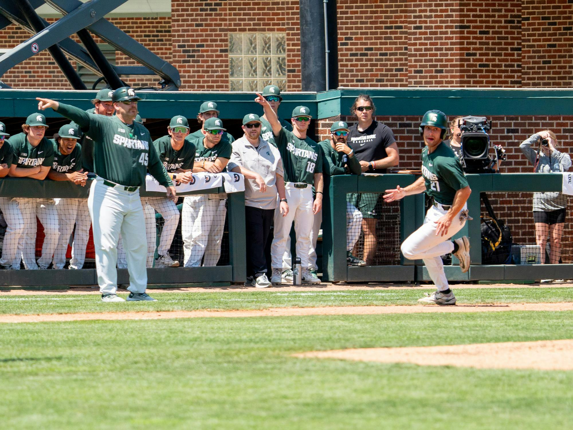 Spartan baseball players in the dugut direct senior outfielder Jack Frank (21) to home plate during a game against University of Nebraska at McLane Stadium on May 17, 2024.