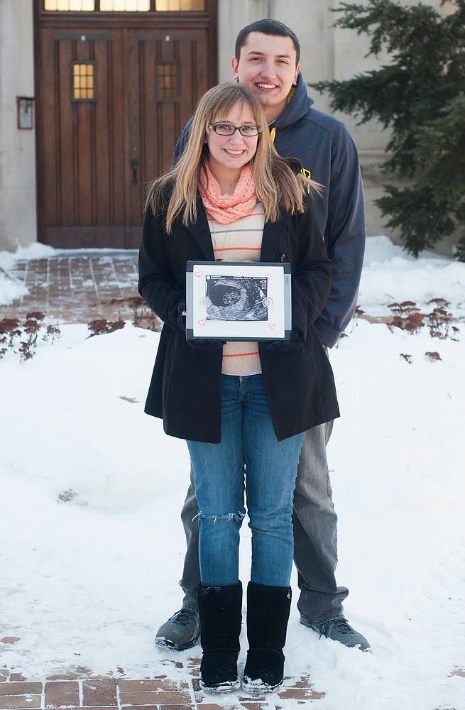 <p>Lansing residents Ashlee Smith and Craig Viavada pose Feb. 15, 2015 in front of Beaumont Tower on 375 W Circle Dr.  The couple is expecting a baby next August. Alice Kole/The State News</p>