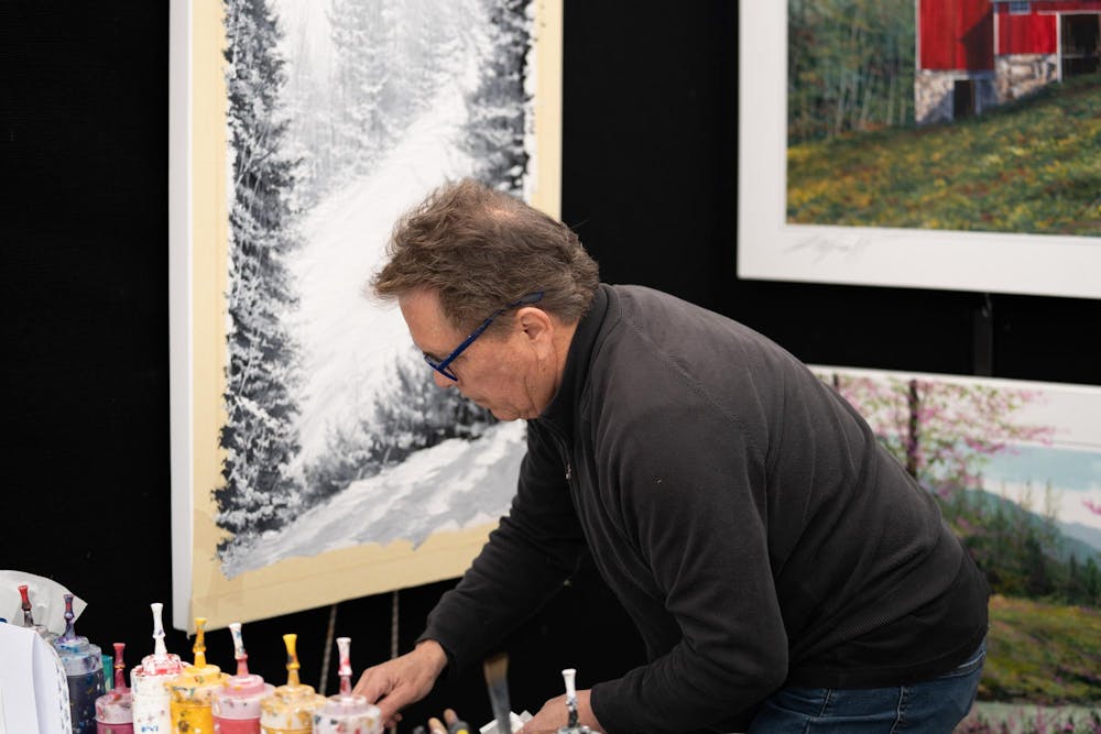 Artist Thomas Legault painting at the East Lansing art festival held across downtown East Lansing on May 20, 2023.