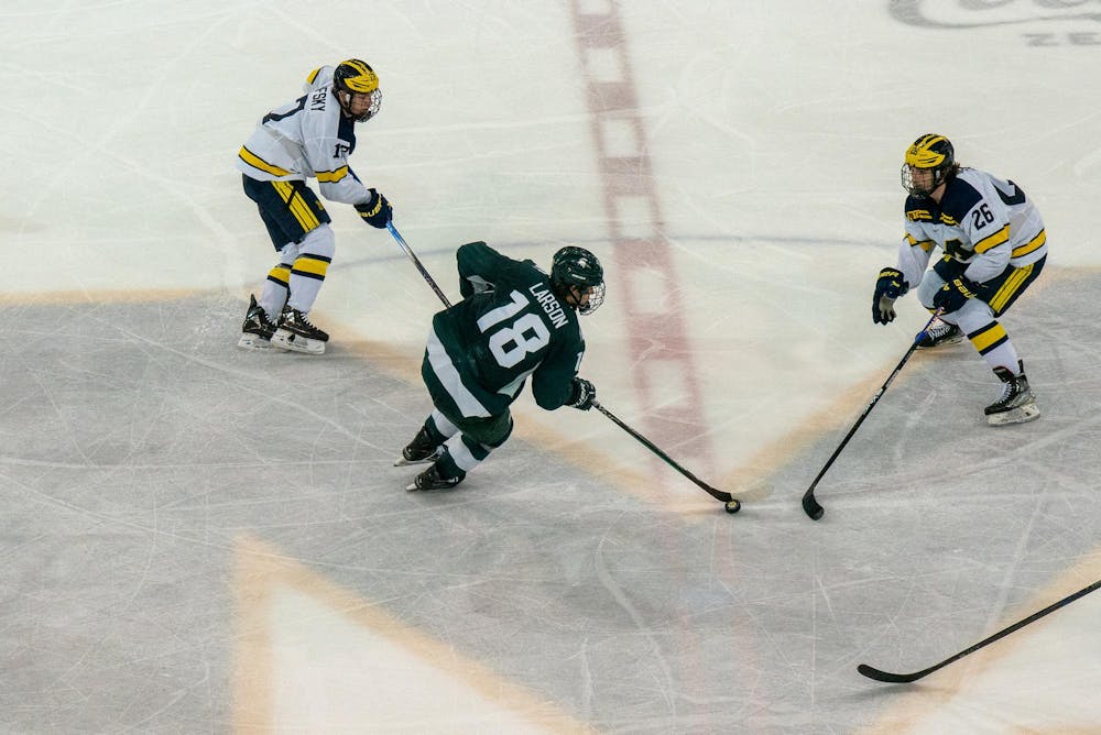 <p>Sophomore forward Joey Larson (18) carrying the puck forward through multiple defenders during a game against University of Michigan at Yost Ice Arena on Feb. 9, 2024.</p>