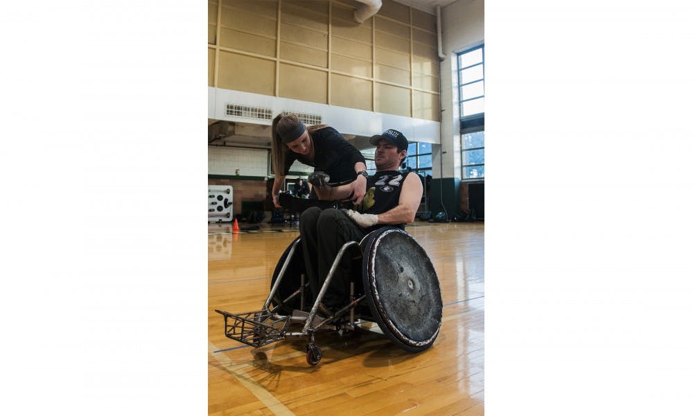 <p>Kinesiology junior&nbsp;Maddie Fisher tapes Andy Zimmer before practice on March 29, 2016 at Jenison Fieldhouse. Fisher volunteers for the Great Lakes Wheelchair Rugby club and helps facilitate practice and traveling for the team.</p>