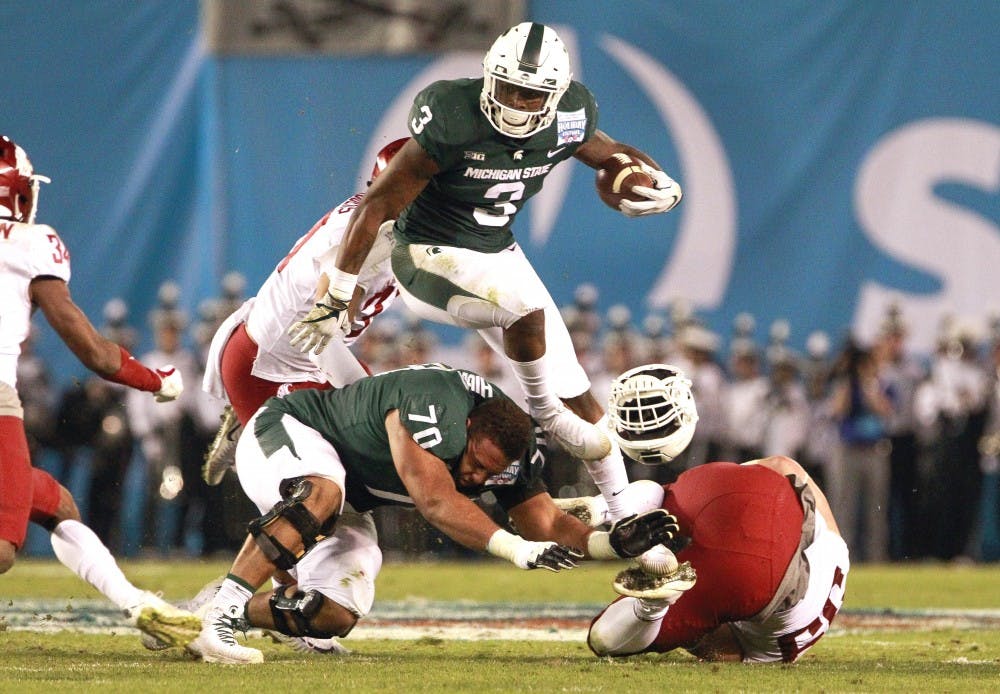 <p>Michigan State's LJ Scott knocks the helmet off his teammate Tyler Higby as he leaps over him while running the ball during the second quarter against Washington State during the Holiday Bowl at SDCCU Stadium in San Diego on Thursday, Dec. 28, 2017. Courtesy of: Hayne Palmour IV/San Diego Union-Tribune/Tribune News Service</p>