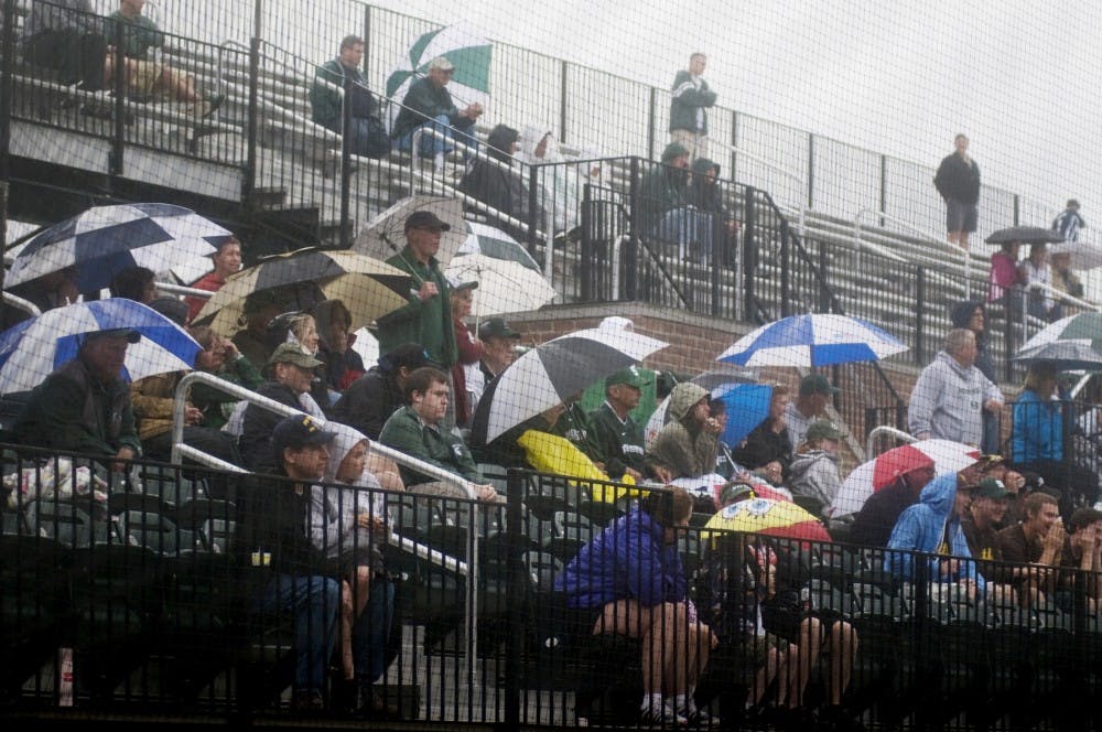 Fans huddle under umbrellas as it began to rain while attending the Michigan State vs. Iowa baseball game Saturday afternoon at McLane Baseball Stadium at Old College Field. The Spartans lost to the Hawkeyes 2-1. Samantha Radecki/The State News