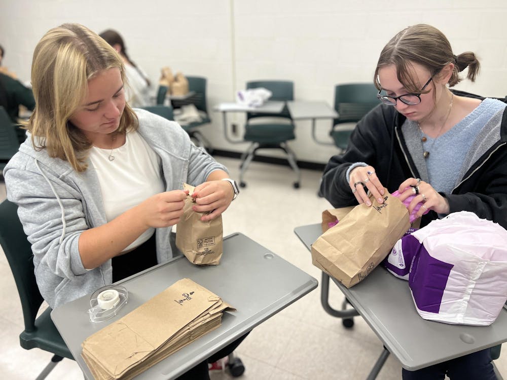 <p>Psychology sophomores Laura Pawlick and Ansley Arnold close their paper bags as they finish packing it with nine pads and six tampons.</p>