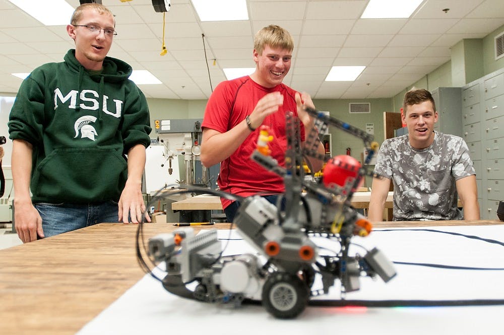 <p>From left, chemical engineering freshmen Charles Shinska, Daniel Marceau and computer science freshman Nick Lojewski watch as their robot completes its task Oct. 3, 2014, in WIlson Hall. The team put in about 50 hours work into their robot, "Wall-O." Dylan Vowell/The State News</p>