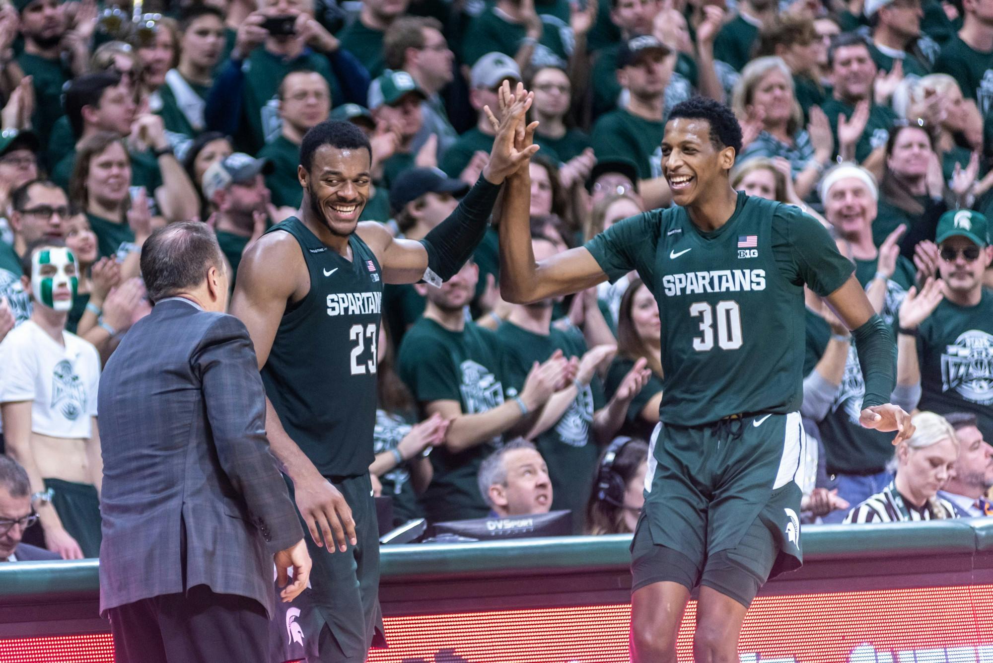 <p>Junior forward Xavier Tillman (23) and sophomore forward Marcus Bingham Jr. (30) high five each other after being subbed out against Illinois. The Spartans defeated the Illini, 76-56, on Jan. 2, 2020 at the Breslin Student Events Center.</p>