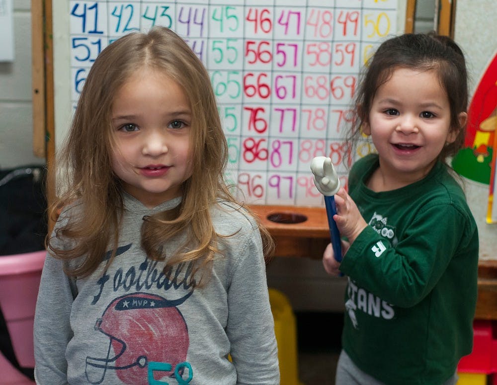 <p>Lansing residents Jossilyn Smith, 2, and Arabella Rosas, 2, smile for a picture March 6, 2015, during playtime at Small Folks Development Center in Lansing. The daycare-preschool encourages diversity and bilingualism by speaking Spanish and English throughout the day. Hannah Levy/The State News</p>