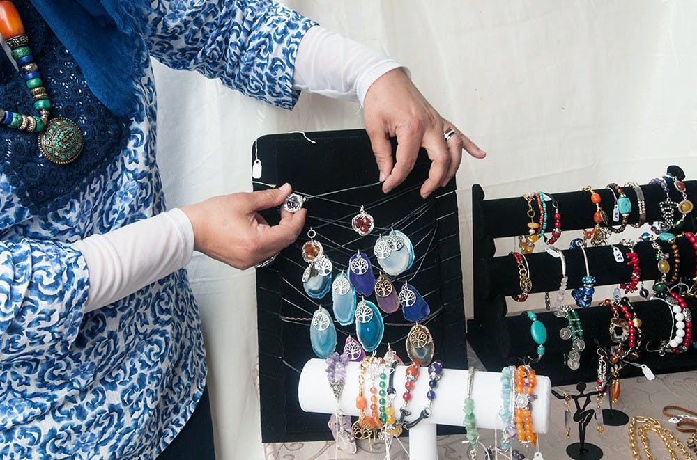 <p>Naglaa Seoudy shows off the prices and the quality of her handmade jewelry to customers May 17, 2015 at the East Lansing Art Festival. Asha Johnson/The State News</p>