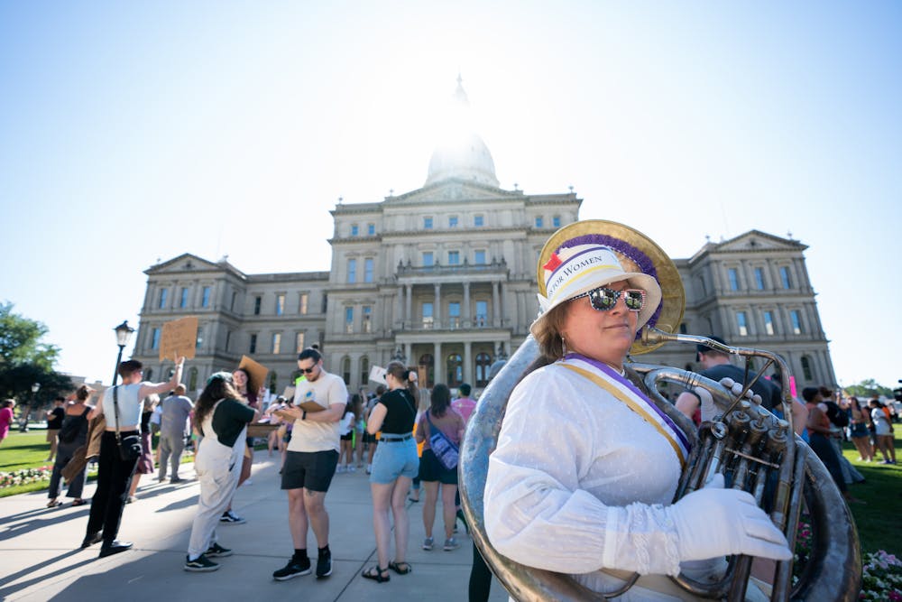 <p>Karen Dunham marches with a helicon in front of the Michigan State Capitol on June 24, 2022. </p><p>&quot;This is a 1909 Helicon which was around during the women&#x27;s movement,&quot; Dunham said. &quot;There were suffragist marches in the 1920s to attain the right to vote and I am sending a message.&quot;</p>