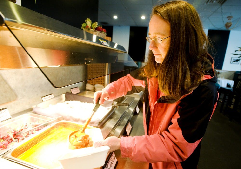 East Lansing resident Ashley Ahlin helps herself as she put some butter chicken onto her take out box Tuesday afternoon at Mumbai, an Indian restaurant at 340 Albert Street. The restaurant offers lunch buffet with authentic Indian taste. Justin Wan/The State News