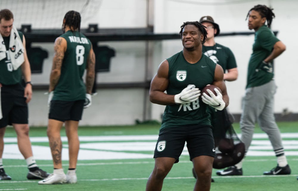 <p>Michigan State junior Kenneth Walker III lets out a smile, after catching the ball while warming up for Pro Day drills, on March 16, 2022 at the Duffy Daugherty Indoor Football Building.</p>