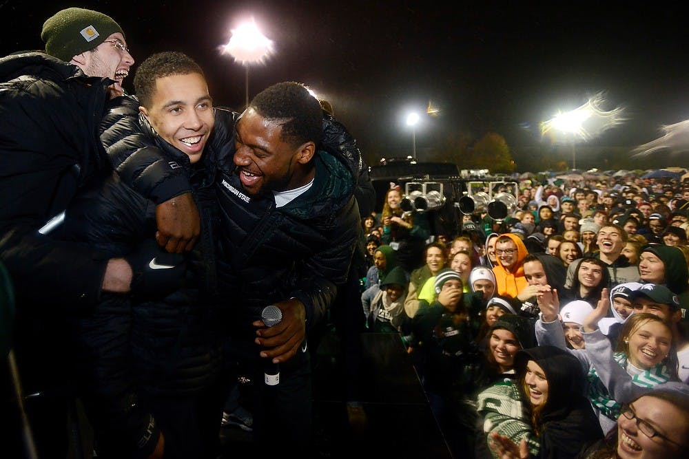 <p>Senior guard/forward Branden Dawson, right, holds onto senior guard Travis Trice after shouting to the crowd he and Trice would crowd surf Oct. 17, 2014, during the Izzone Campout at Munn Field. Hundreds of students battled the cold and rain to sleep outdoors overnight in hopes of getting lower bowl seating. Julia Nagy/The State News</p>