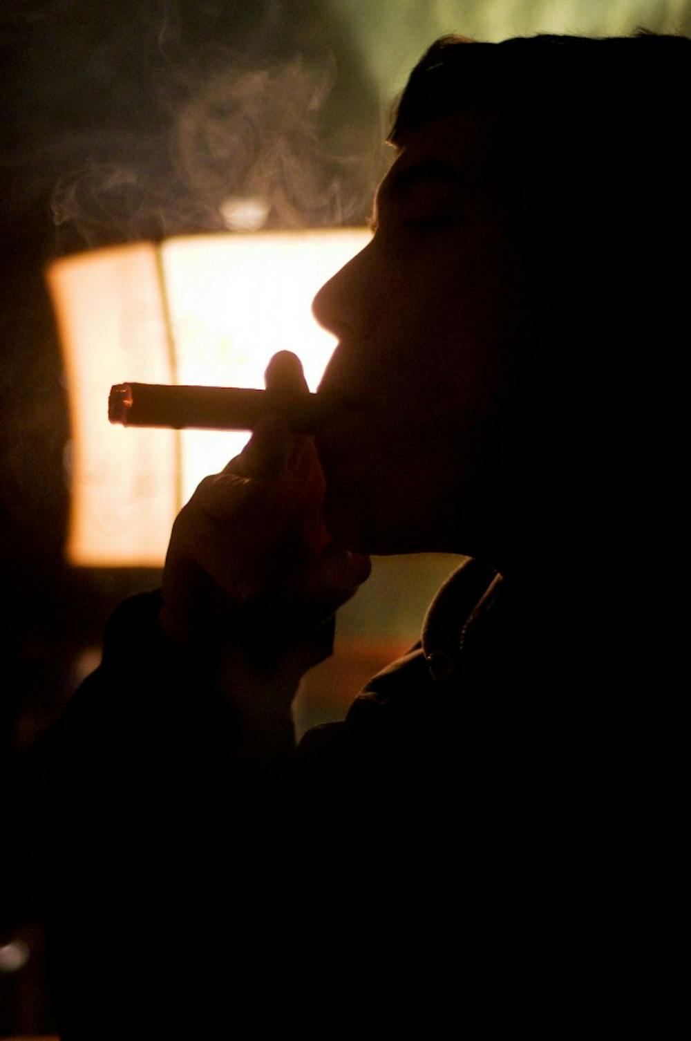 Finance junior Phil Garrett smokes a cigar Friday at Corona Smoke Shop, 3490 Okemos Road, Okemos, Mich. Garrett is a member of the MSU Cigar Connoisseur's Club, a club intended to teach members about cigars and provide social gatherings for cigar smokers. Matt Radick/The State News