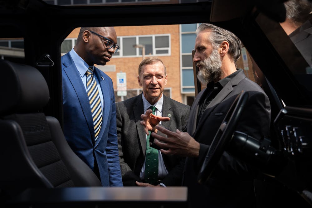 <p>MSU President Samuel L. Stanley and Michigan Lieutenant Governor Garlin Gilchrist II speak with Bollinger Motors CEO Robert Bollinger after the roundtable. Gilchrist visited MSU for a roundtable discussion on electric vehicles on April 20, 2022.</p>