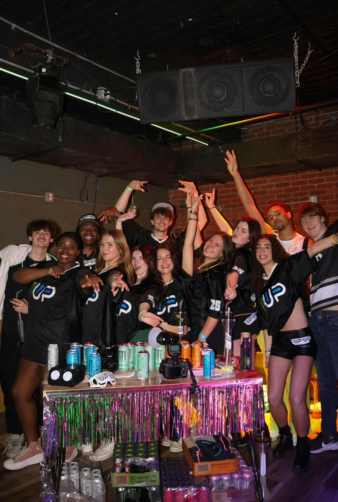 <p>Members of Up &amp; Up pose with Monster Energy merchandise at a club event.</p>
