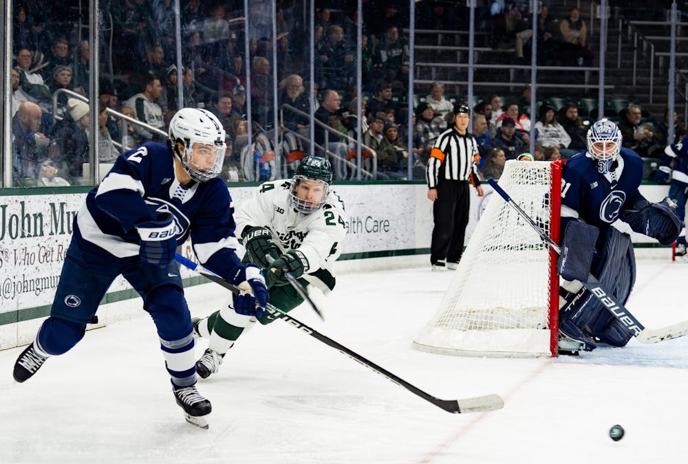 <p>Senior forward Erik Middendorf (24) tries to push past Penn State University player during a game at Munn Ice Arena on Jan. 13, 2023. The Spartans defeated the Nittany Lions with a score of 3-2. </p>