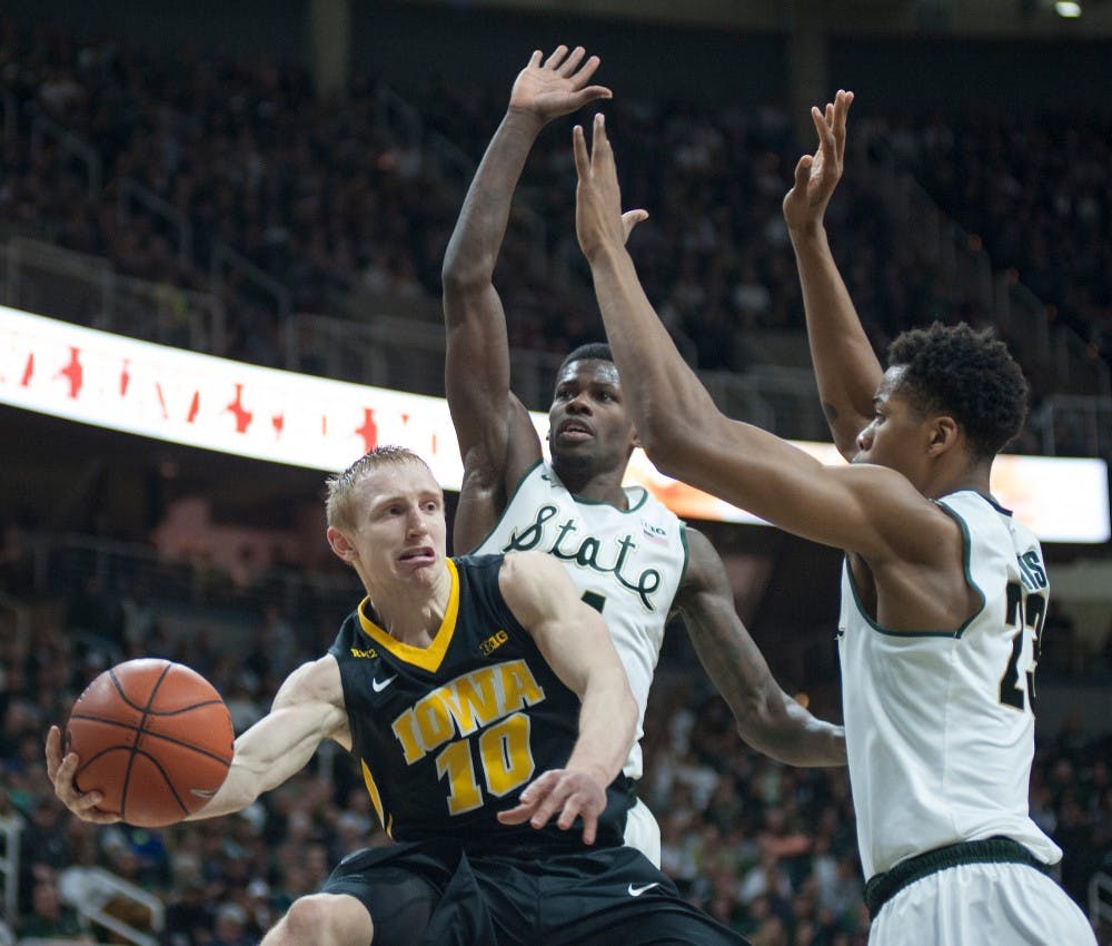Iowa guard Mike Gesell looks to pass the ball as he is defended by Eron Harris, 14, and freshman forward Deyonta Davis during the game against Iowa on Jan. 14, 2016 at Breslin Center. The Spartans were defeated by the Hawks, 76-59 .