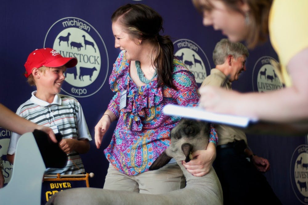 	<p>Saranac, Mich. resident Sarah Kennedy, grand champion of market sheep division, chats with Grand Rapids, Mich. resident Tommy Suter, 10, who bought sheep from her after an auction, July 16, 2013, at the Michigan Livestock Expo at the <span class="caps">MSU</span> Pavilion. Governor Rick Snyder addressed the show earlier the day. Justin Wan/The State News</p>