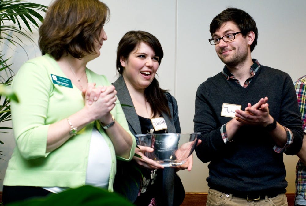 	<p>Center, creative writing senior Danae Voss laughs as political theory and constitutional democracy senior Thomas Bunting and East Lansing resident Erin Carter applaud after the Community Relations Coalition received a Crystal Award Thursday evening at the Hannah Community Center. Four recipients were recognized at the 24th annual Crystal Awards reception that was held to honor outstanding members of the East Lansing community. </p>