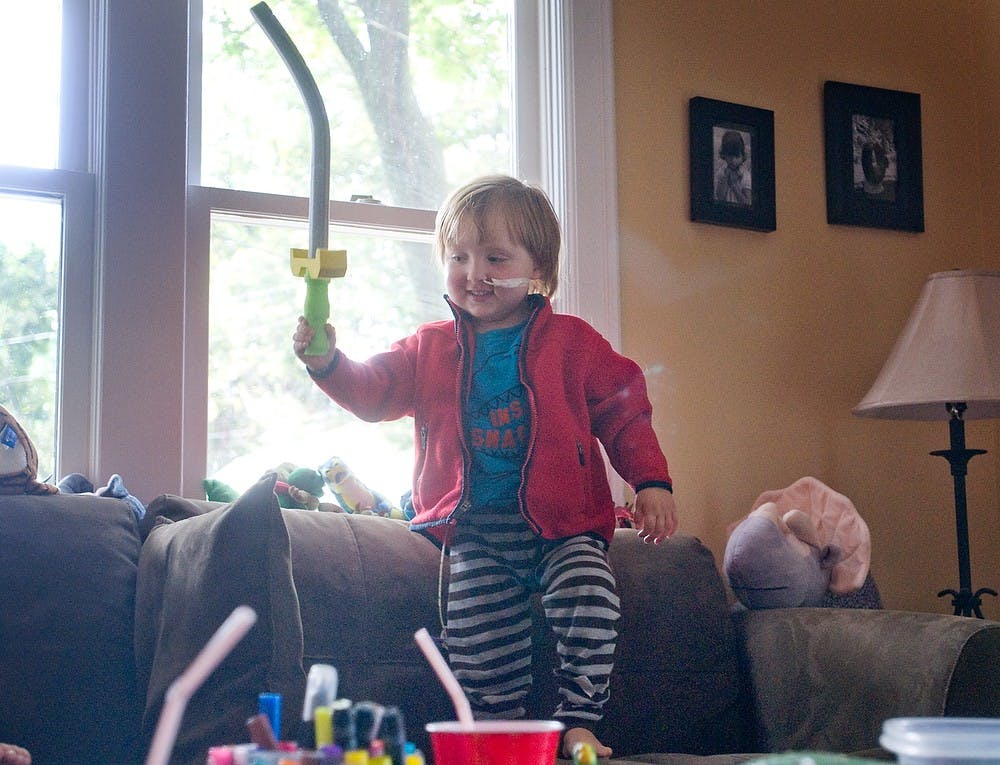 	<p>Charlie Waller, 3, walks across his couch with a foam sword on Aug. 30, 2011, in his East Lansing home. Charlie was diagnosed with a rare form of brain cancer in April, but he continues to battle the disease with  a new ketogenic diet. Matt Radick/The State News</p>