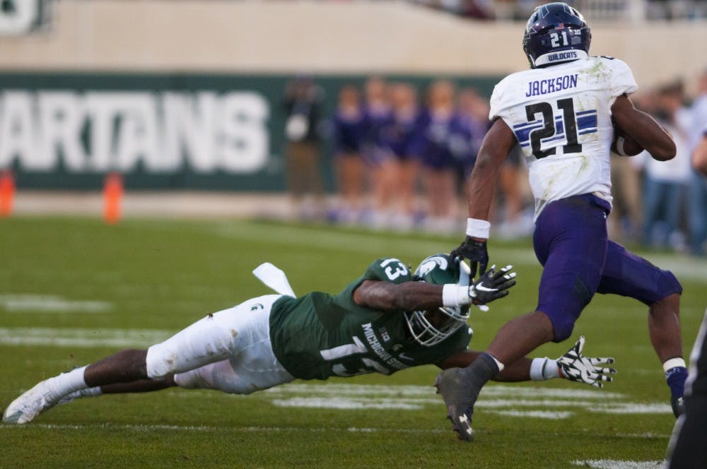 Sophomore defensive back Vayante Copeland (13) attempts to tackle Northwestern running back Justin Jackson (21) during the game against Northwestern on Oct. 15, 2016 at Spartan Stadium.  The Spartans were defeated by the Wildcats, 54-40.  