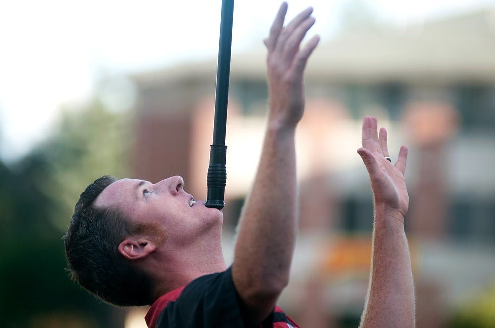 <p>Bay City, Mich., resident Joel Tacey balances a 12-foot pole with a basket of eggs on it on his chin July 8, 2014, at Valley Court Park. When the pole finally fell the audience saw that the eggs were not real but rather a plastic set used for magic tricks. Jessalyn Tamez/The State News</p>