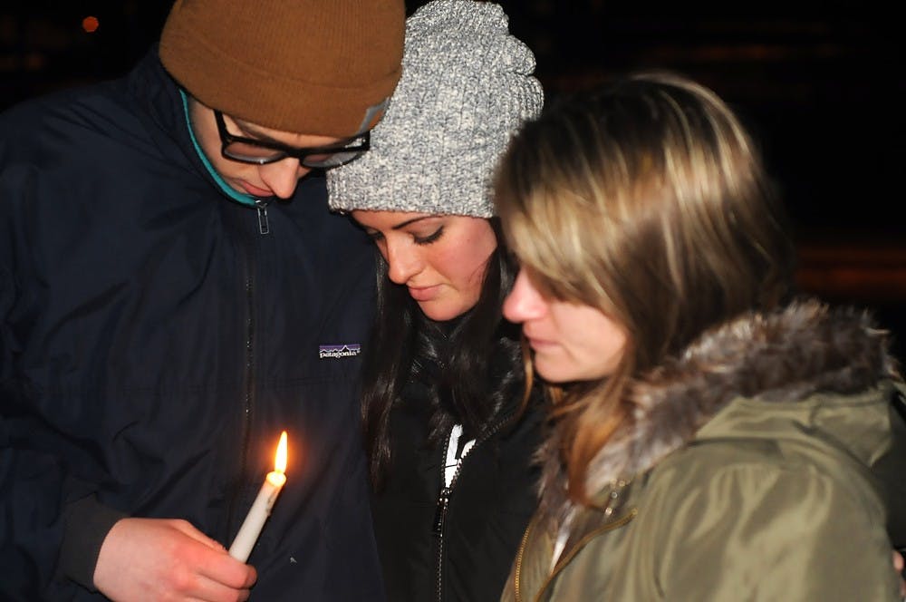 <p>Political theory junior and Sigma Pi brother Andrew Brewster, and neuroscience freshman Sabrina Saracino, middle, comfort mechanical engineering sophomore Celeste Stawiarska, right, Jan 30, 2015, during the candlelight vigil held at the The Rock on Farm Lane in honor of Stawiarska’s boyfriend and applied engineering sciences senior Anthony Hawley. Kennedy Thatch/The State News</p>