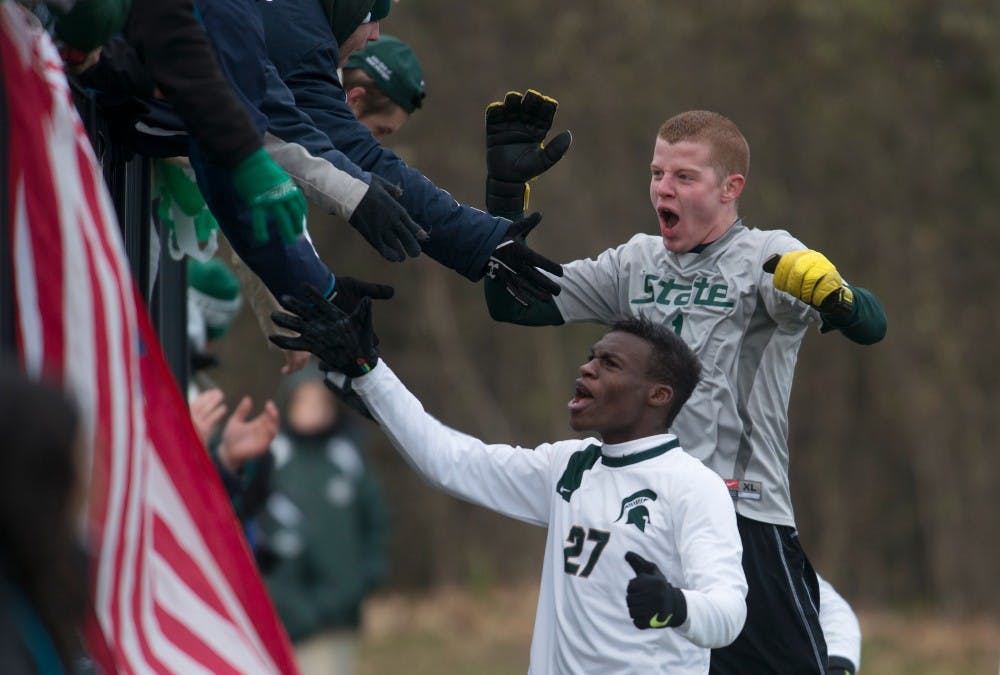 <p>Then-junior midfielder Fatai Alashe, 27, and then-sophomore goalkeeper Zach Bennett celebrate with the Red Cedar Rowdies on Nov. 24, 2013, after defeating Louisville during the second round of the NCAA tournament at DeMartin Stadium at Old College Field. The Spartans defeated the Cardinals 1-0 in double overtime. State News File Photo</p>
