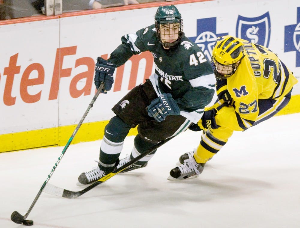 Sophomore defense Jake Chelios looks up ice as Michigan forward Alex Guptill tries hit the puckl loose. The Spartans fell to the Wolverines 3-2 in overtime Saturday night at Joe Louis Arena. Anthony Thibodeau/The State News