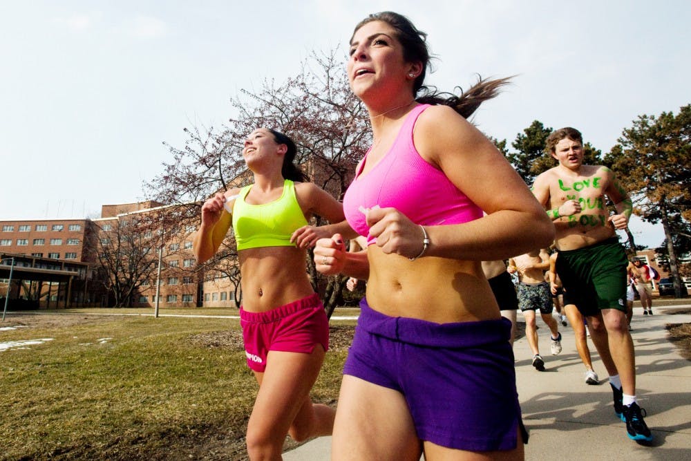 Engineering freshman Dominique Dubay, right, and psychology freshman Kelsey Loveland run through South neighborhood Friday afternoon during South Side Stride for Pride. The event brought scantily clad students out to run through campus in an effort to raise awareness about body image. Matt Hallowell/The State News