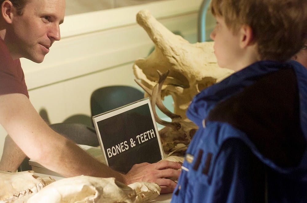	<p>Volunteer Kevin McCormick describes the skulls of a wolverine and a giraffe to Holt resident Baisil Mullen, 9, on Feb. 9, 2014, at the <span class="caps">MSU</span> Museum. The Darwin Discovery Day event gathered children and adults of all ages from Michigan to experience exhibits discussing reptiles, birds, bugs and more. Sierra Lay/The State News</p>