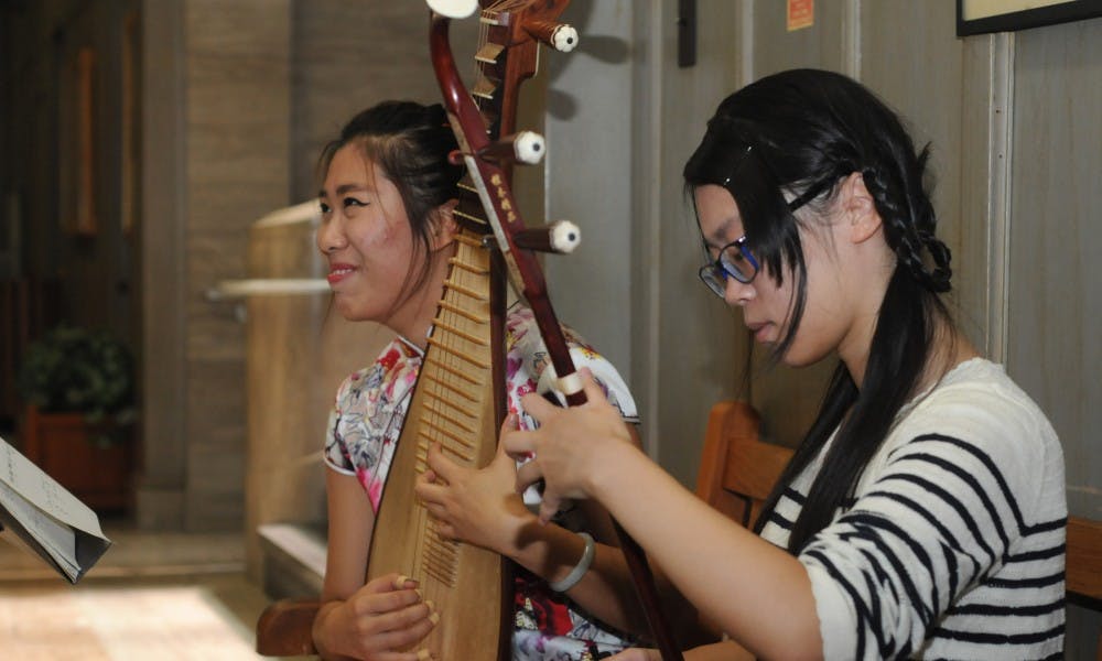 <p>Journalism freshman Zimo Wang, left, and accounting sophomore Shiyun Zeng practice before performing on Sept. 27, 2015 inside the MSU Museum. Zimo and Zeng were some of the few people who performed classical Chinese music during the grand opening of the Quilts exhibit.</p>