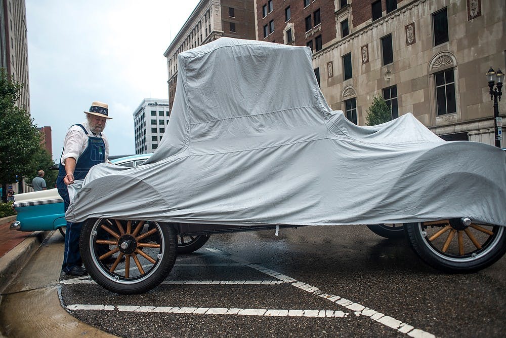 	<p>Hell, Mich., resident Michael Brady adjusts a rain cover for his 1925 Ford Model T, July 27, 2013, in downtown Lansing during the Car Capital Auto Show 2013. The 21st annual event was organized by the R.E. Olds Transportation Museum. Justin Wan/The State News</p>