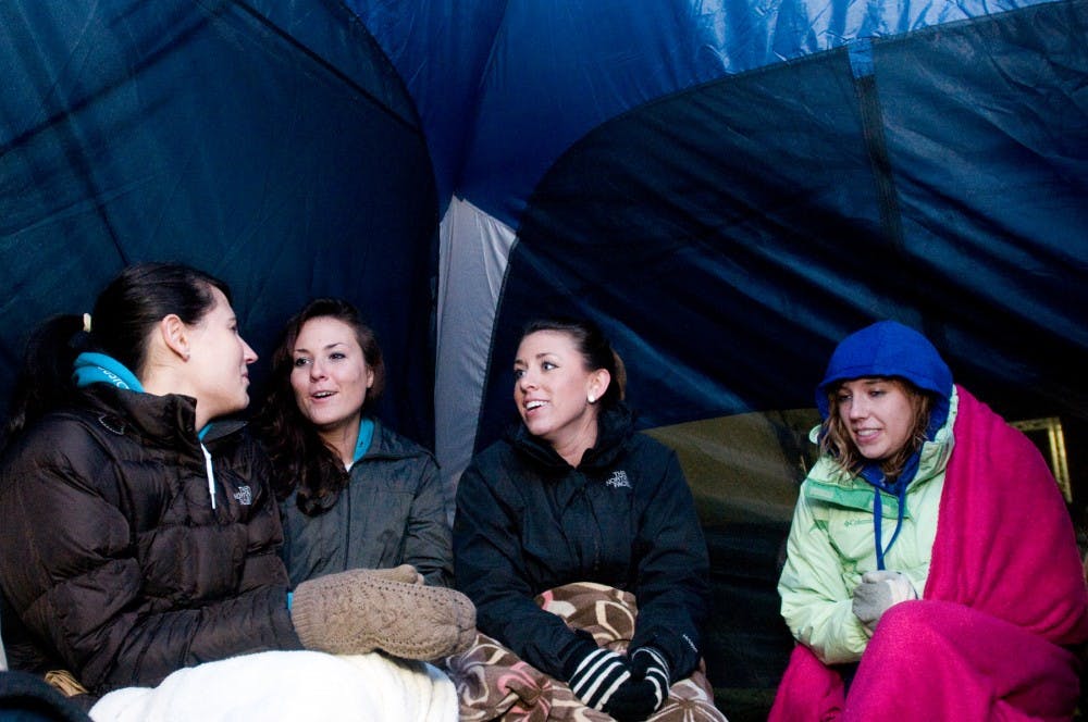 From left to right, Ellen Fehl, Lindsey Guinall, Emily Norton and Shannon Lizotte, all senior interior design students, bundle up in their tent to stay warm during Relay for Life Friday at Munn Field. The friends participated in Relay for Life through the Interior Design Student Organization at Michigan State University. Jaclyn McNeal/The State News