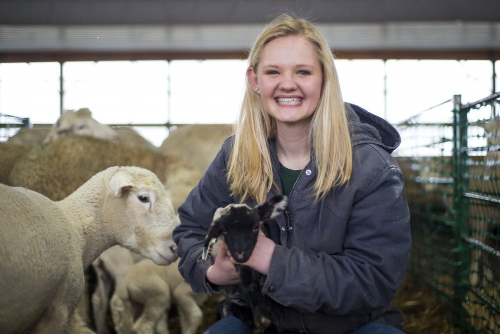 Animal science sophomore Emmy Schuurmans poses for a portrait with a lamb on March 2, 2017 at the Sheep Teaching and Research Center in Okemos, Mich. Schuurmans is the only student who lives at the farm house and during lambing season she would check the ewes at 9 p.m., midnight and 6 a.m. to check for newborn lambs to assist in the birthing process. 