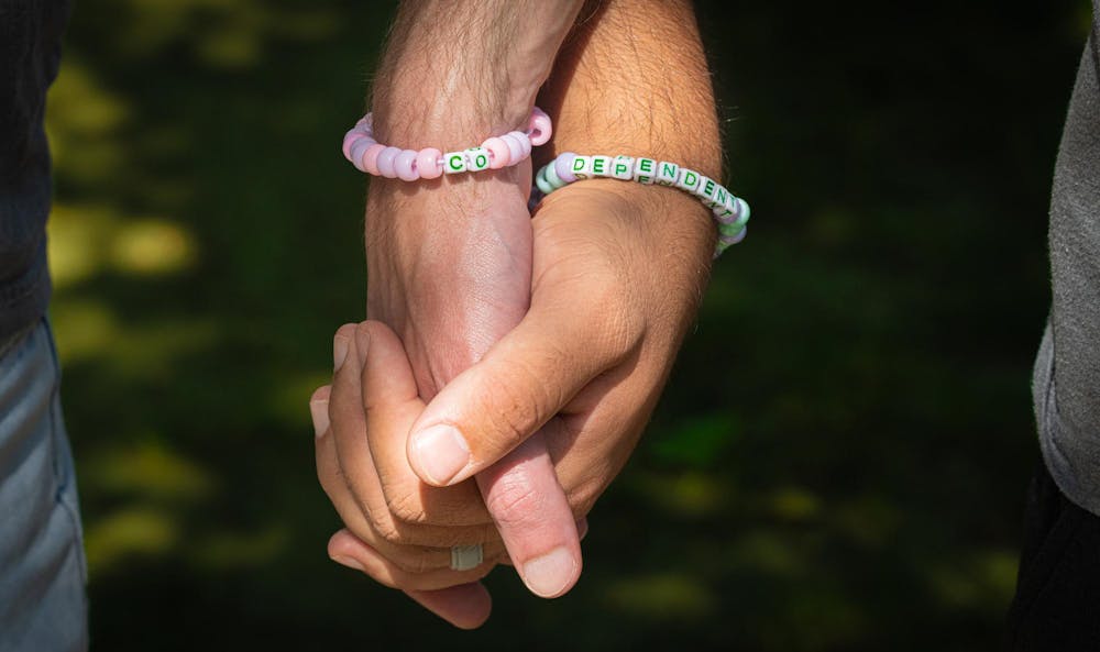 <p>A photoillustration of two people holding hands wearing bracelets.</p>