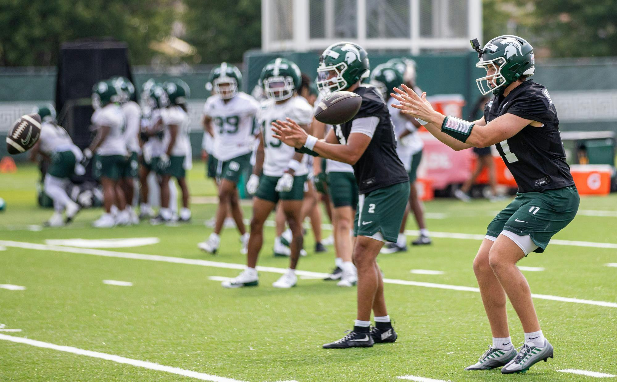 <p>Michigan State QB's, Alessio Milivojevic (11, right) and Cam Fancher (2, left), prepare to recieve the ball during a practice at the MSU Duffy Daugherty practice fields in East Lansing, Mich., on Aug. 6, 2026.</p>