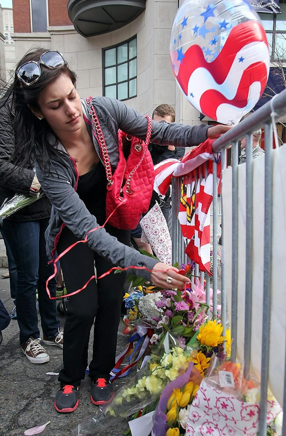 	<p>Isabelle Atkinson places a balloon and flowers at a makeshift memorial near the bombing site on Tuesday,  April 16, 2013, in Boston, Massachusetts. The city is in mourning today for three killed and at least 144 wounded in the bombing at the Boston Marathon. (Matt Stone/Boston Herald/MCT)</p>