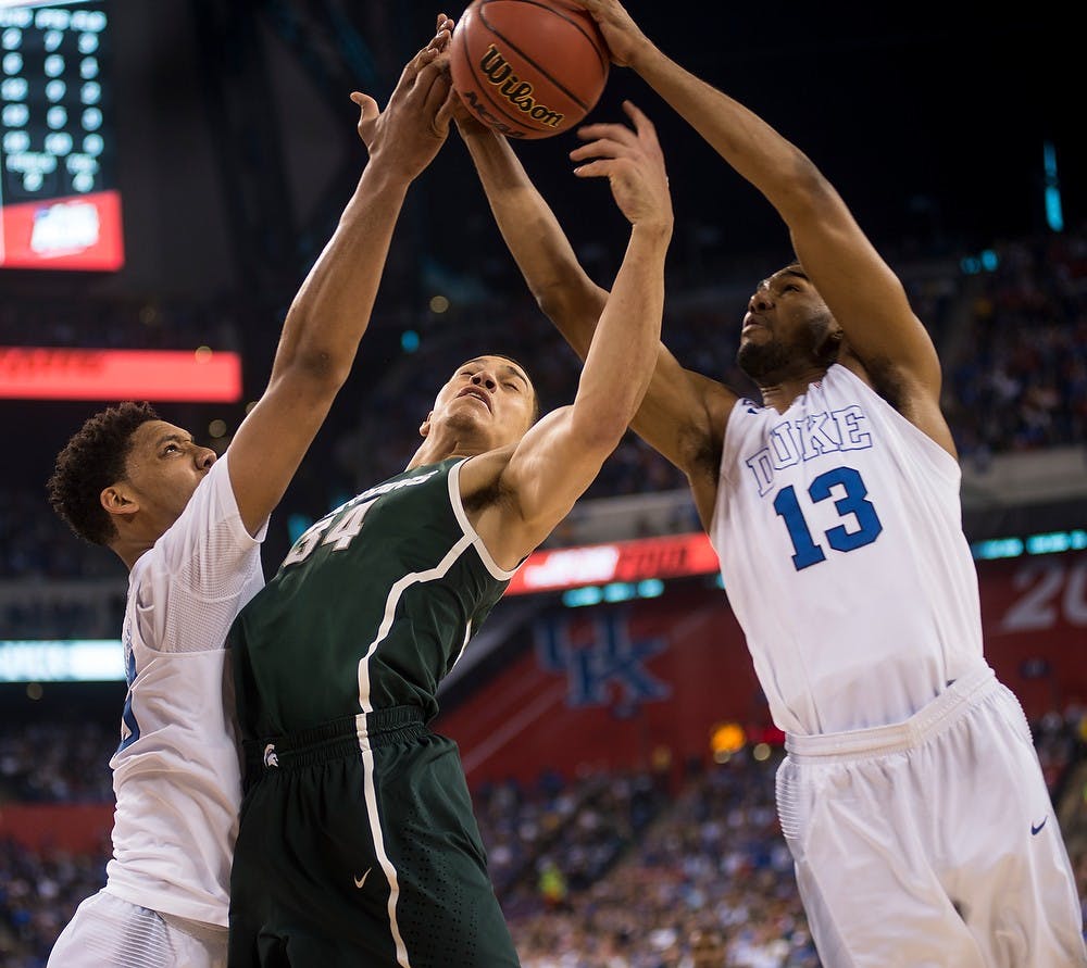 <p>Senior forward Gavin Schilling is blocked by Duke guard Matt Jones, 13, and center Jahlil Okafor and April 4, 2015, during the semi-final game of the NCAA Tournament in the Final Four round at Lucas Oil Stadium in Indianapolis, Indiana. The Spartans were defeated by the Blue Devils, 81-61. Erin Hampton/The State News</p>