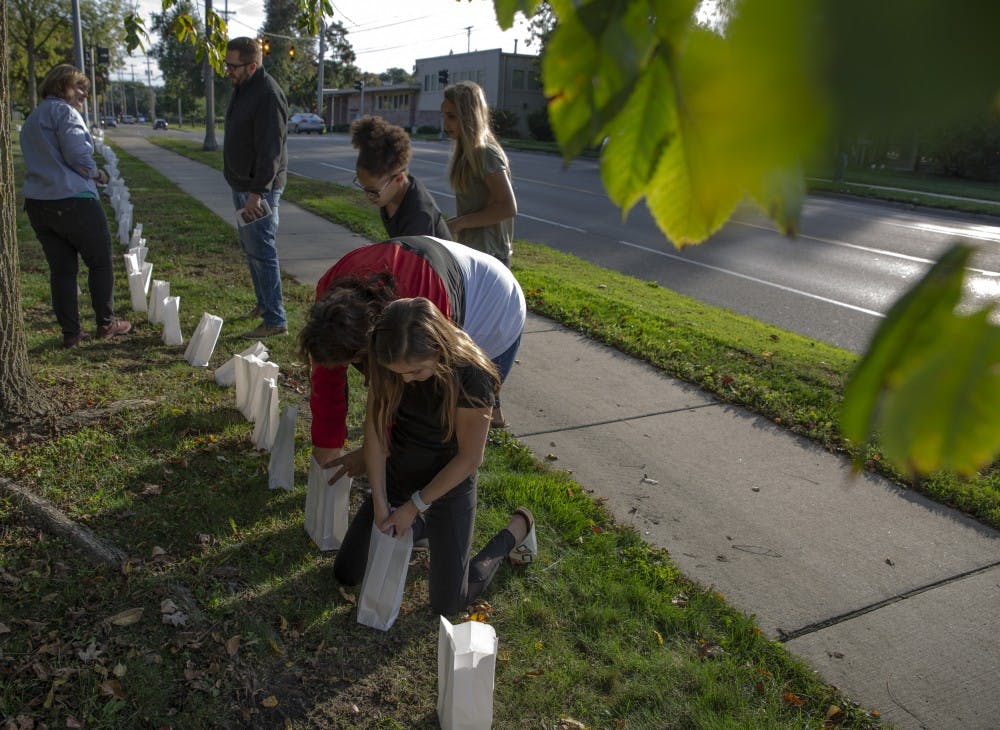 A family lights candles on Oct. 10, 2019 at the East Lansing Public Library. POSSE lit 505 luminaries signifying the known survivors Larry Nassar at the East Lansing Public Library, before President Stanley’s meeting with survivors. 
