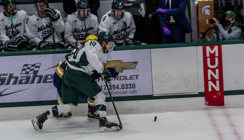 Freshman A.J. Hodges (10) fights with a Notre Dame defender for possession of the puck in the second period. The Fighting Irish shutout the Spartans 2-0 on Feb. 27, 2021.