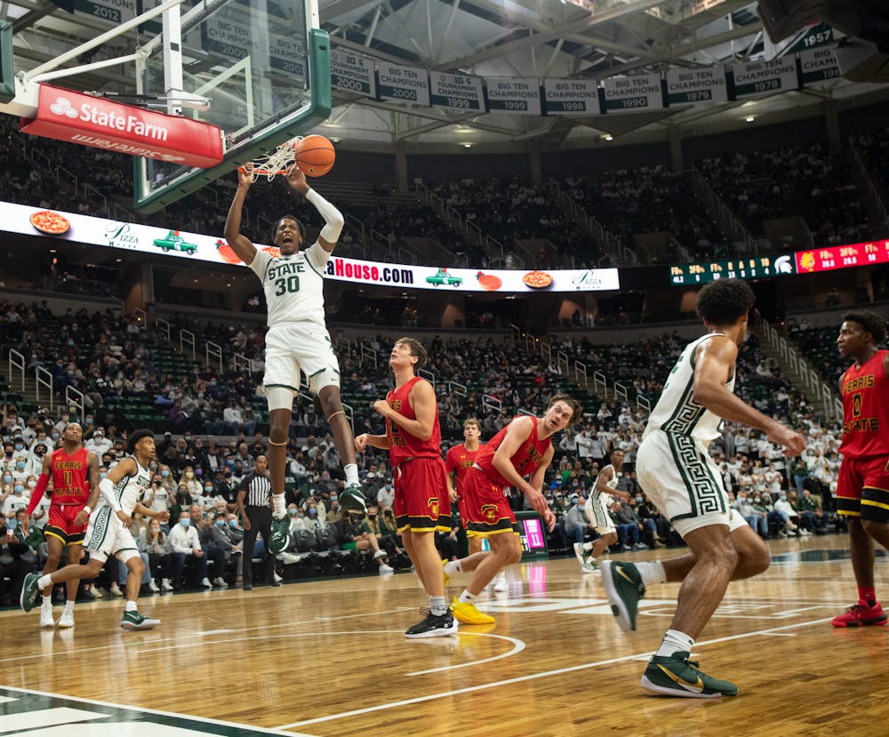 <p>Michigan State&#x27;s senior forward Marcus Bingham Jr. holds onto the rim after dunking during Michigan State&#x27;s victory over Ferris State on Oct. 27, 2021.</p>