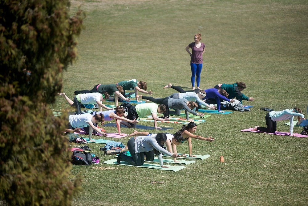 <p>Participants practice yoga April 8, 2014, at the Rock on Farm Lane for Mental Health Awareness Week. Students could stop by in-between classes and pick up free yoga mats to participate in the event. Julia Nagy/The State News</p>