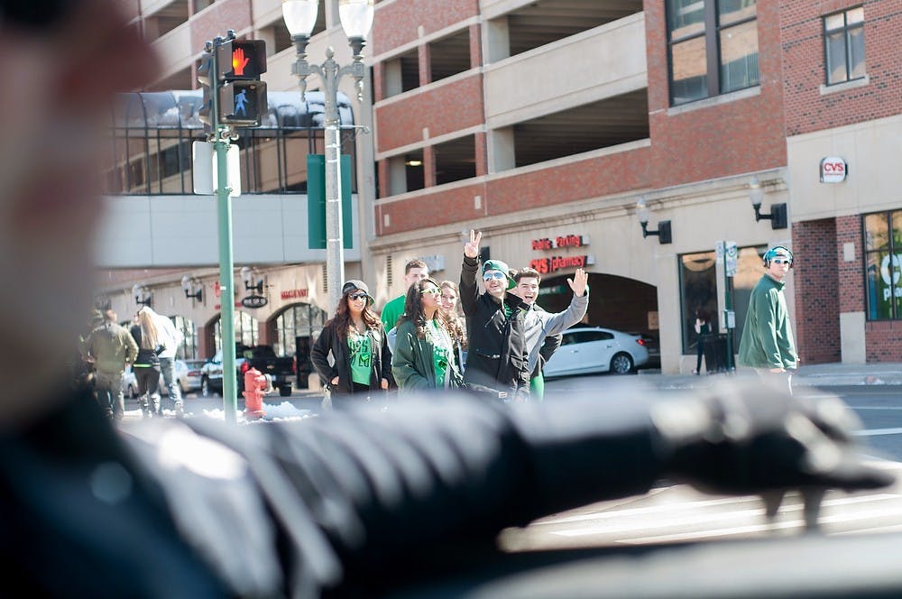 <p>People wish Sgt. Marc Smith a “Happy St. Patrick’s Day” on March 17, 2013, on M.A.C. Ave. During his ride, Smith got everything from well wishes to “I hate you” from people walking. Julia Nagy/The State News</p>