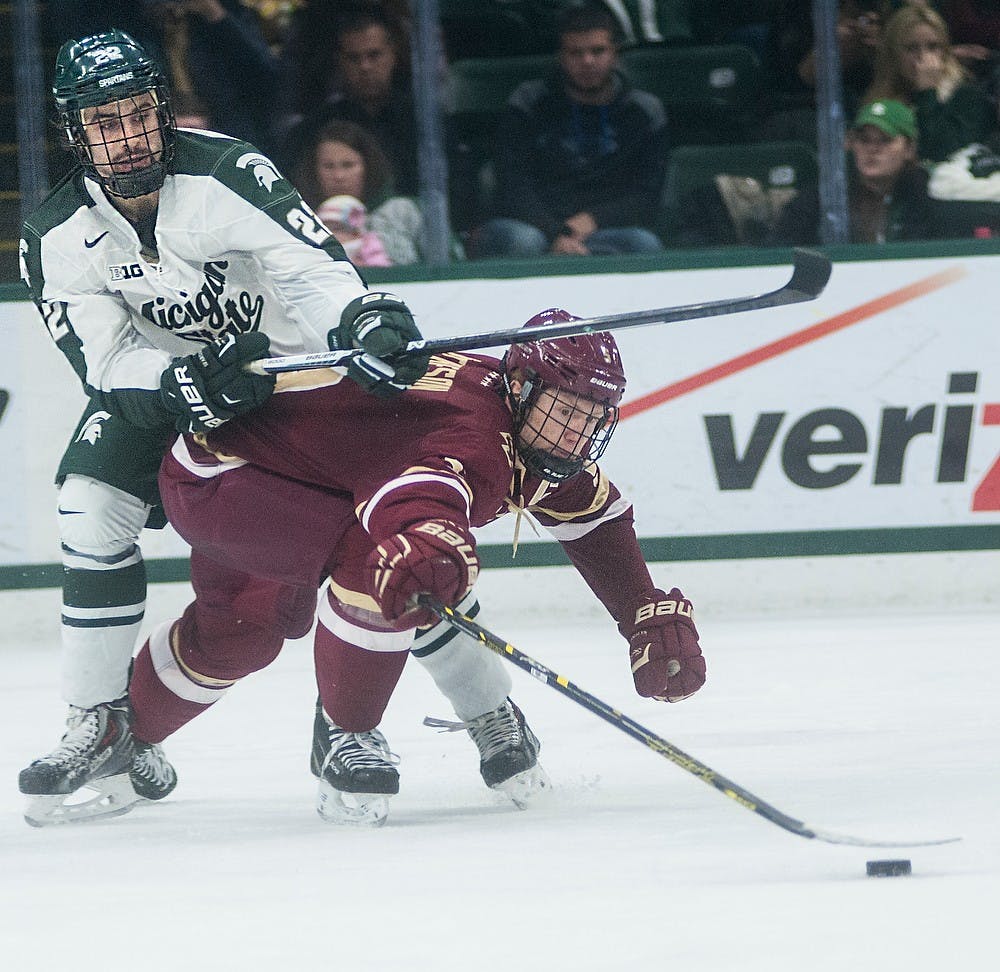 <p>Sophomore forward JT Stenglein fights for the puck with Boston College defenseman Michael Matheson Nov. 14, 2014, during the game at Munn Ice Arena. The Spartans lost to the Eagles, 3-2. Erin hampton/The State News</p>