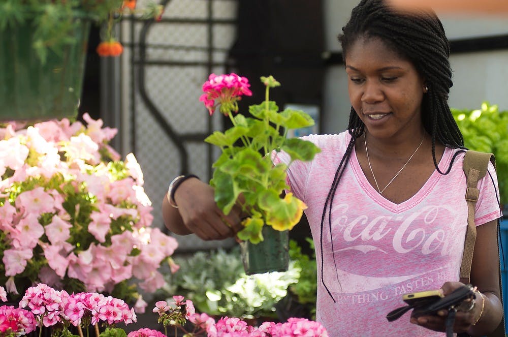<p>Communication senior Maevea Bottex holds flowers June 8, 2014 at the East Lansing Farmers Market behind Biggby Coffee. The market opened for the first time this summer. Hayden Fennoy/The State News</p>